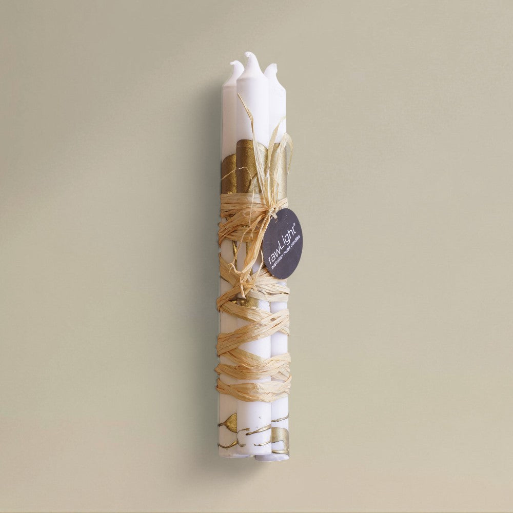 Three white-and-gold splashed Christmas dining candles