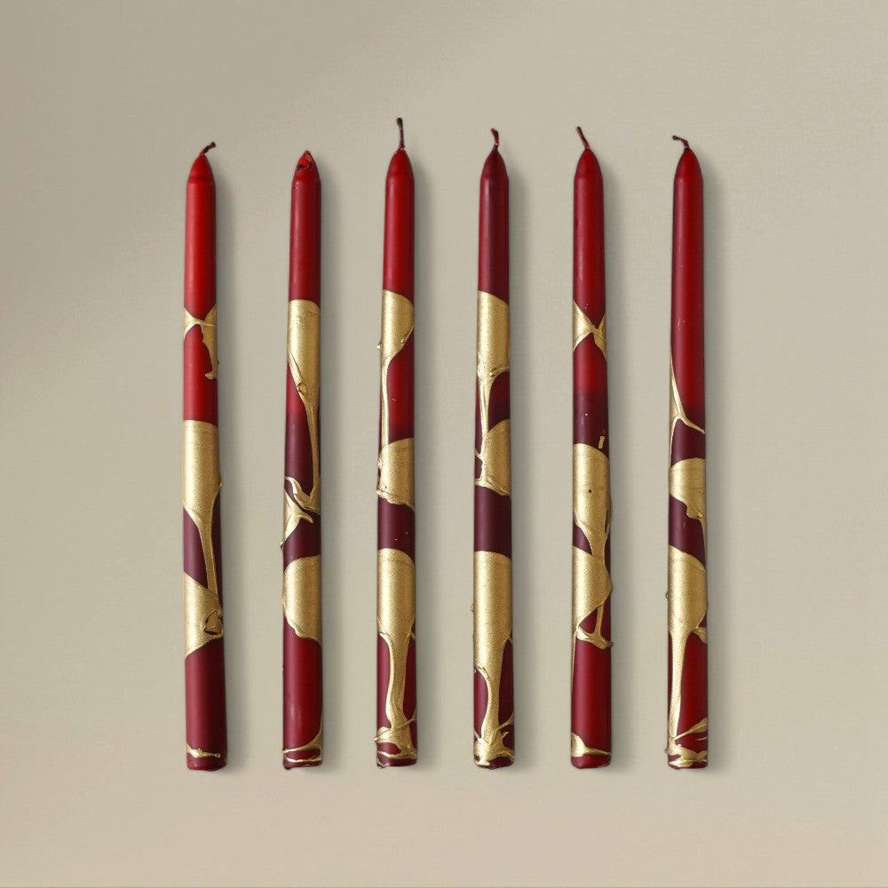 Six red-and-gold splashed Christmas taper candles