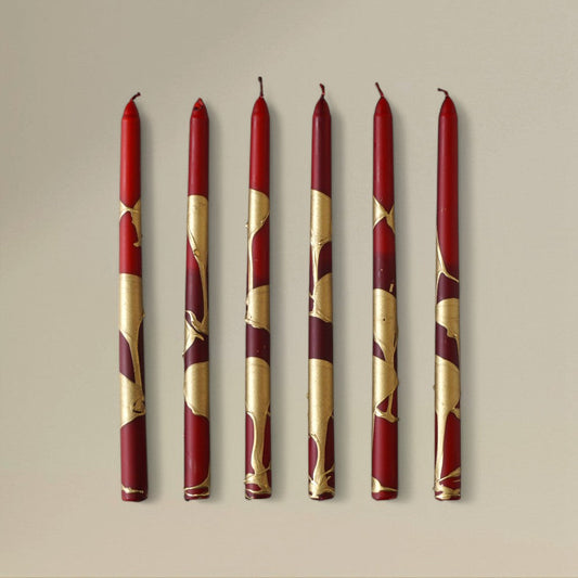 Six red-and-gold splashed Christmas taper candles